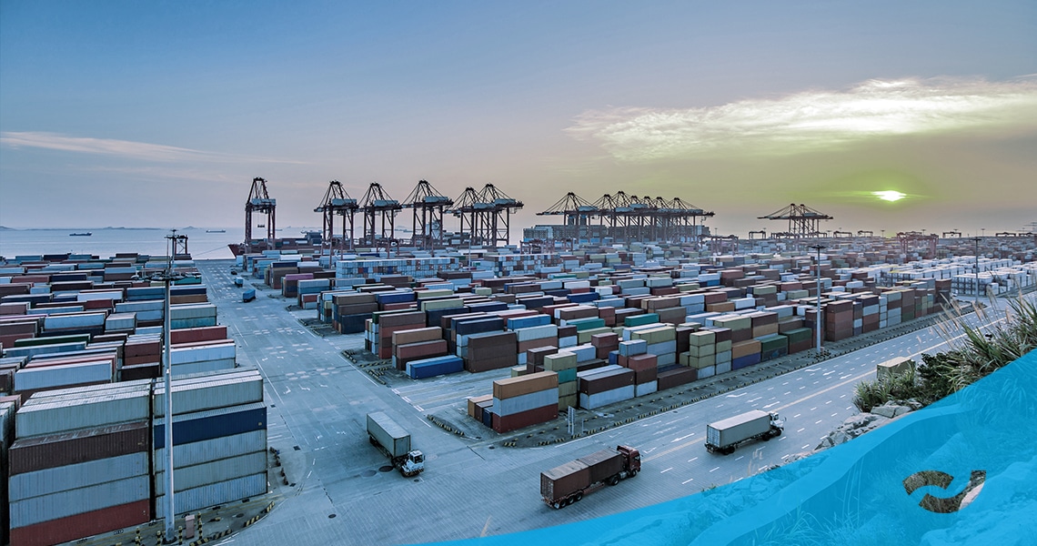 Branchenbild für Handelsunternehmen. Container Ladeplatz an einem Hafen im Hintergrund. Vorne im Bild sind LKWs zu sehen die die Container abtransportieren.